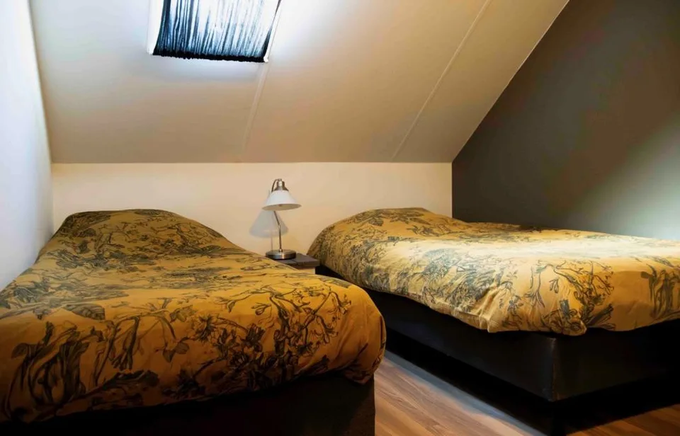 Slaapkamer onder schuin dak met twee bedden